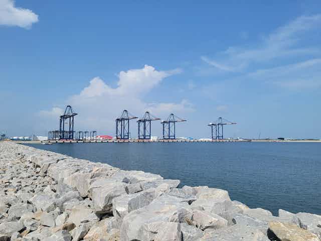 A view of a port in the sea, with crane fixtures showing in the background.