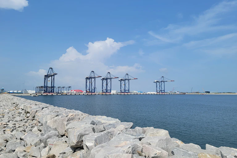 A view of a port in the sea, with crane fixtures showing in the background.