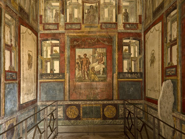 A room with walls coloured in colourful frescos of nude men and women.