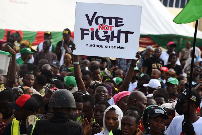 A man lifts up a placard in the midst of a crowd