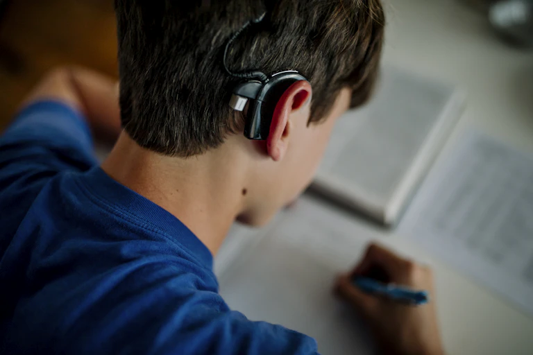 Person with cochlear implant doing homework