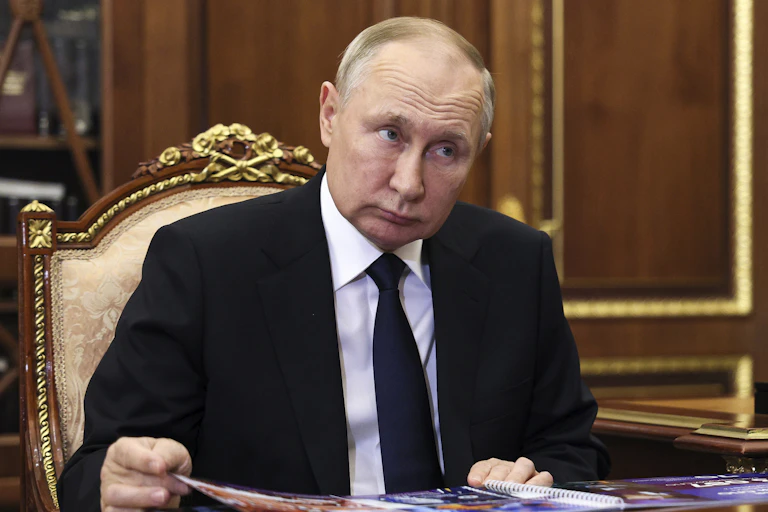 A balding man looks to the left at someone speaking off-camera.