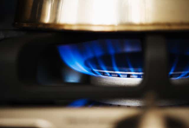 Blue flame rising from a gas burner under a pot