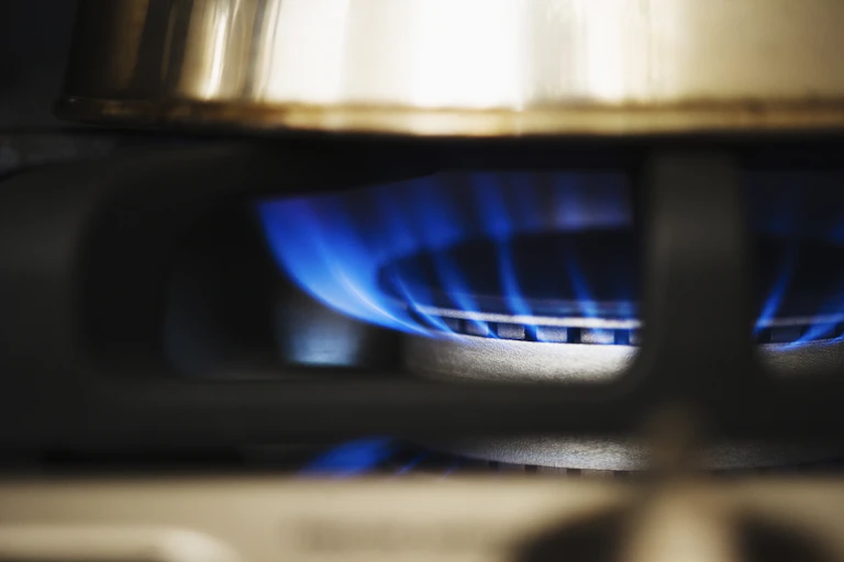 Blue flame rising from a gas burner under a pot