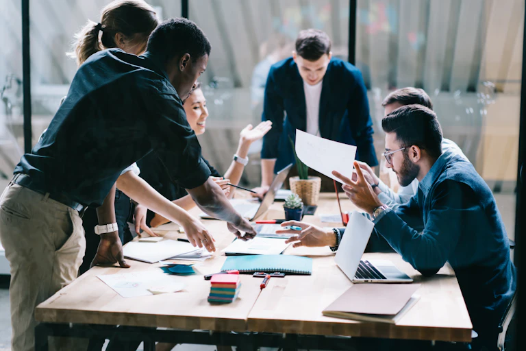 A diverse group of people brainstorming around a small conference table