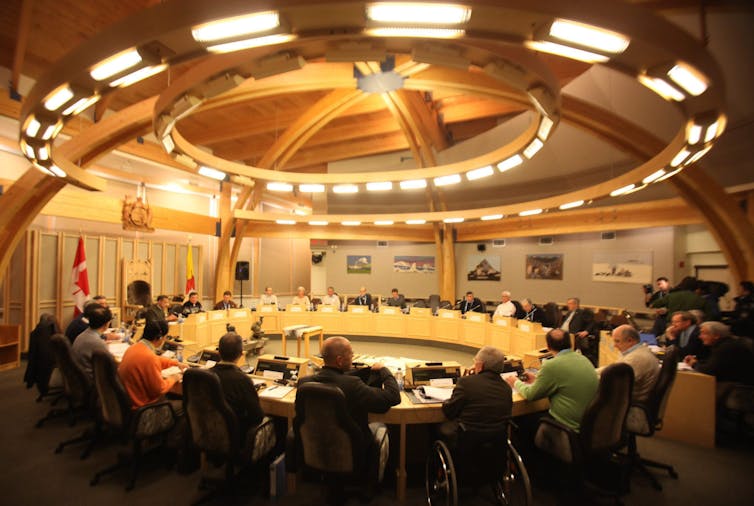 People seen sitting in desks designed in a circle format.