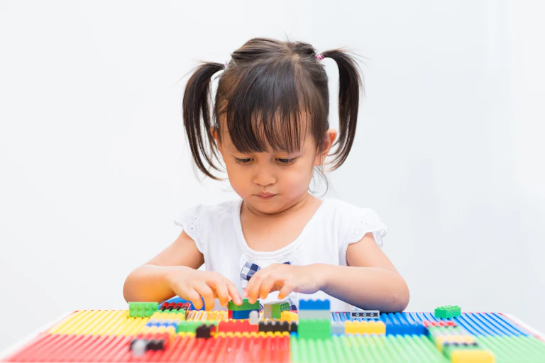Little girl playing with building blocks