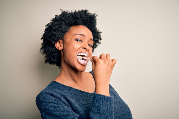 Black woman cleaning teeth.