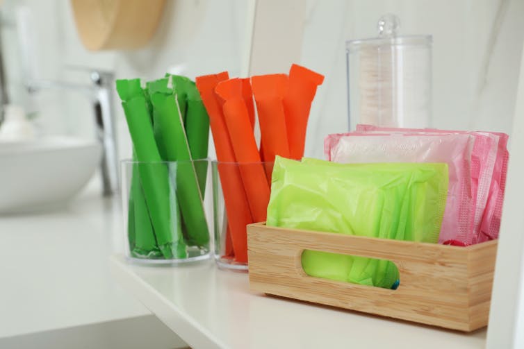 Period products in containers on a bathroom shelf