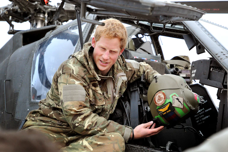 Close-up of a man dressed in military uniform sitting near a military helicopter.
