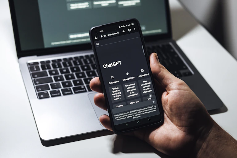 A hand holding a phone with the ChatGPT interface displayed on it