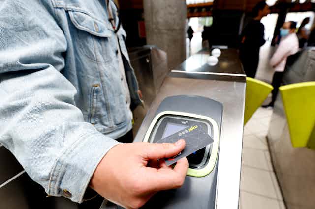 Person's handing holding a myki card against a public transport ticket reader