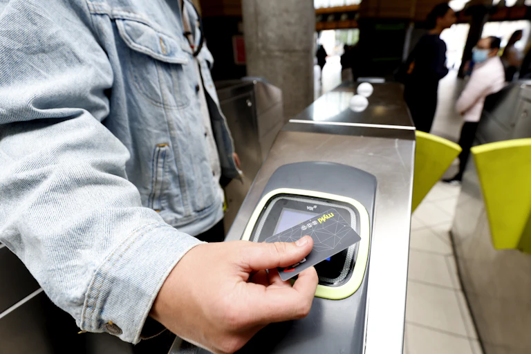 Person's handing holding a myki card against a public transport ticket reader