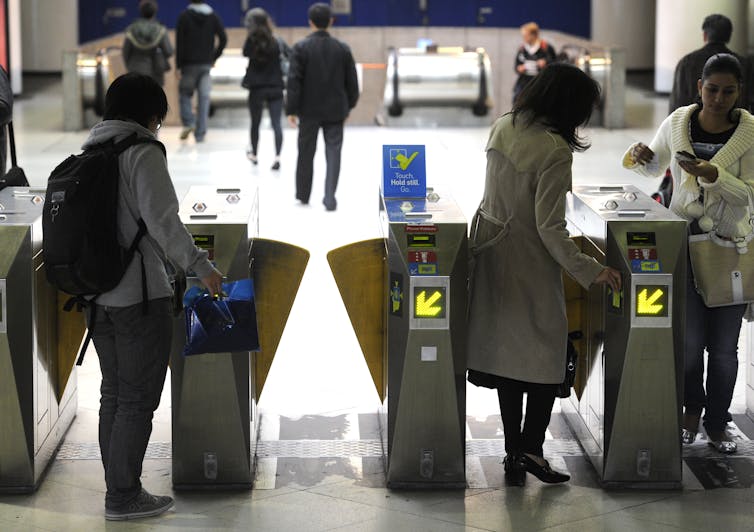 People present their myki cards to pass through the barriers at a public transport station