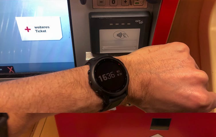 Person holds their smart watch against a scanner to pay for their  trip on public transport.