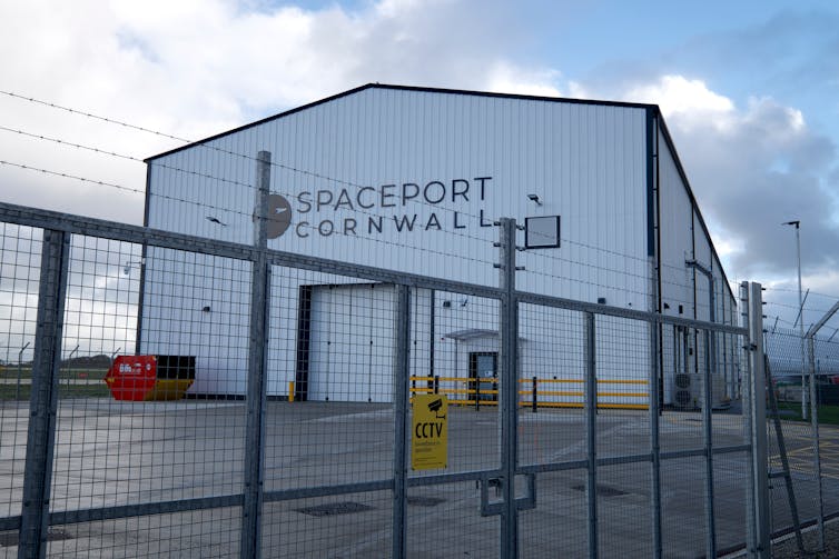 Um hangar branco com o Spaceport Cornwall marcado na frente.