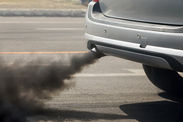 A car exhaust emitting a plume of black smoke.