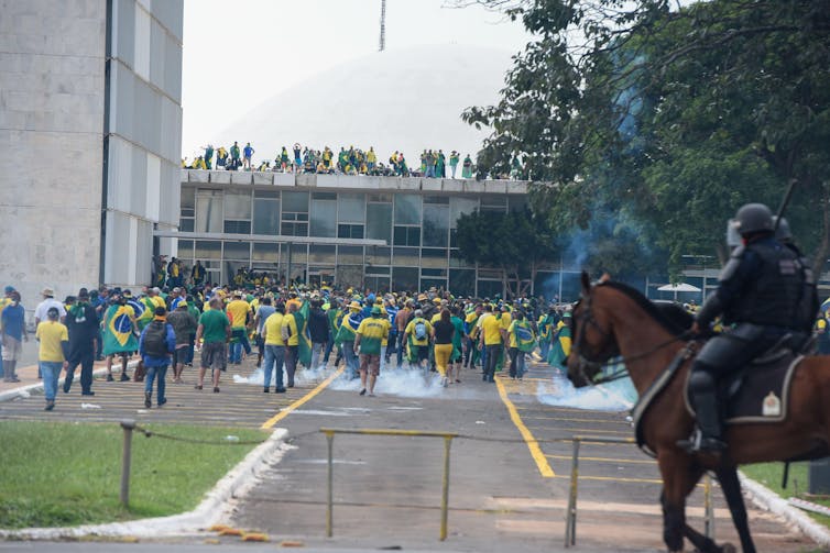 A police officer on a horse, and a large crowd of people.