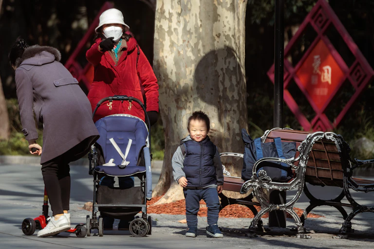 A young Chinese boy with two adults and a pushchair.