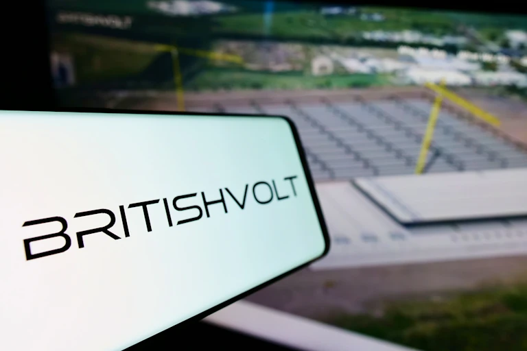 A smartphone displaying a Britishvolt logo in front of an artist's impression of the gigafactory.