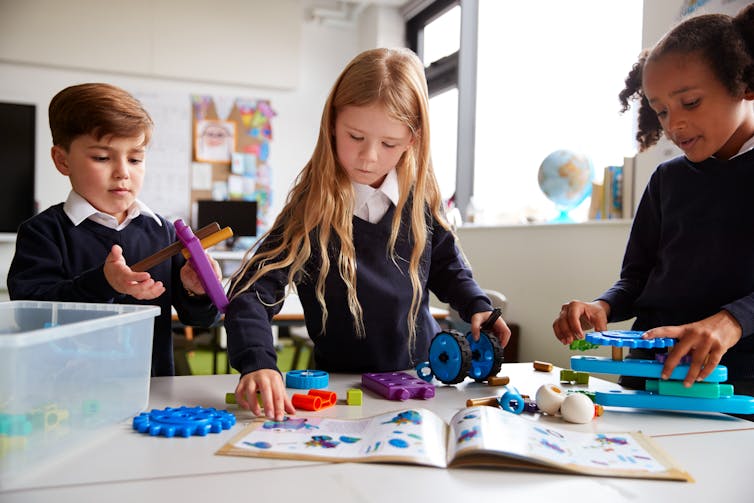 Children in classroom following instructions to build with parts