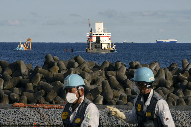 Two construction workers against the backdrop of construction works underway at sea.