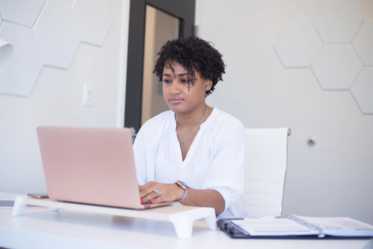A woman seated at a desk with an open laptop