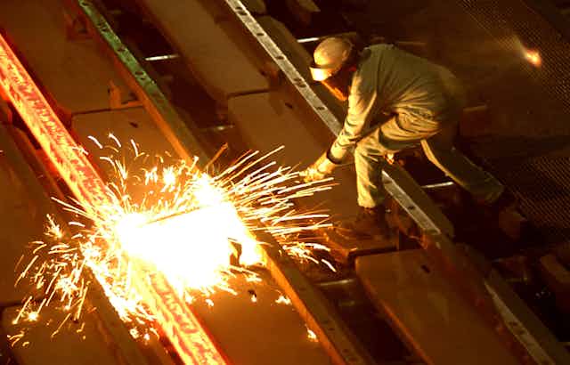 A worker cuts through glowing steel at a  U.S. steel mill.