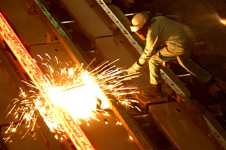 A worker cuts through glowing steel at a U.S. steel mill.