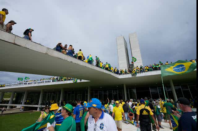 People in bright yellow and green clothes gather outside a large building.