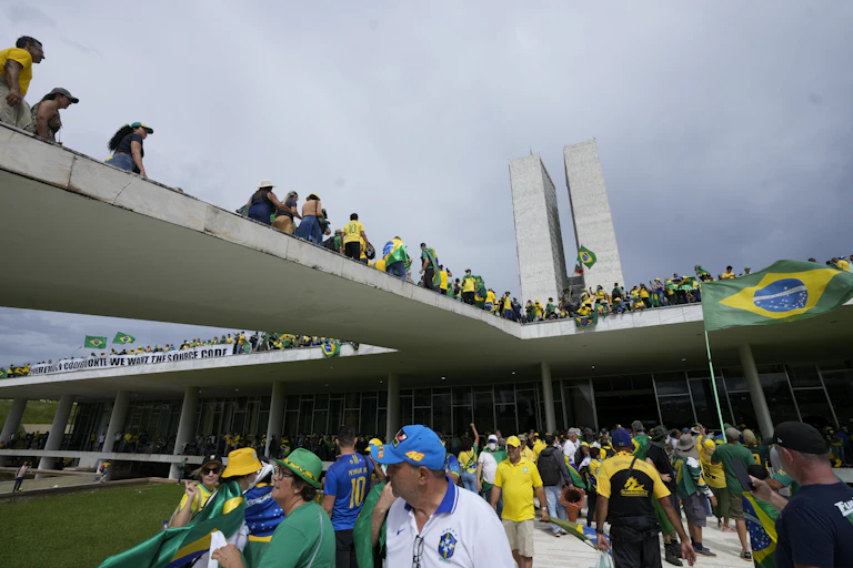 People in bright yellow and green clothes gather outside a large building.