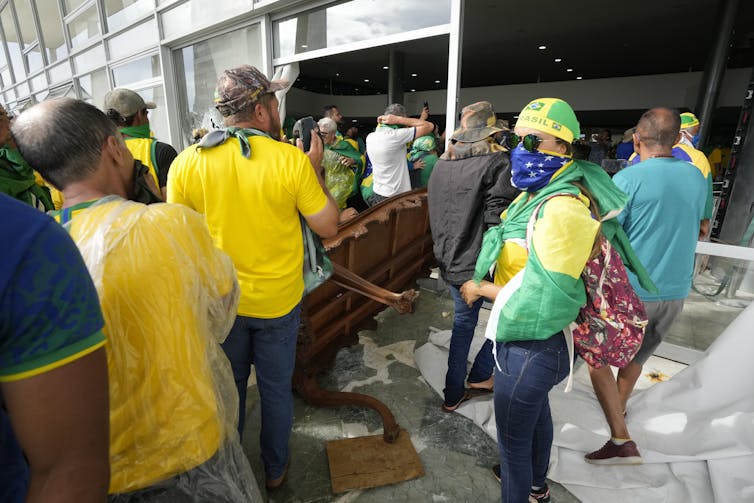 People, some wearing masks and hats, enter a doorway.