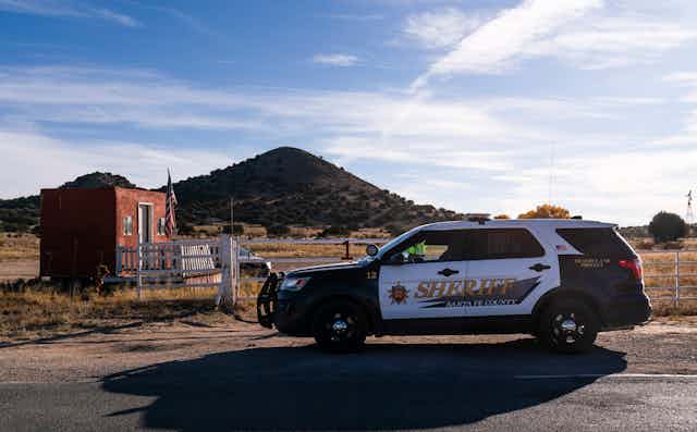 A sheriff's car parked next to a fence in New Mexico.