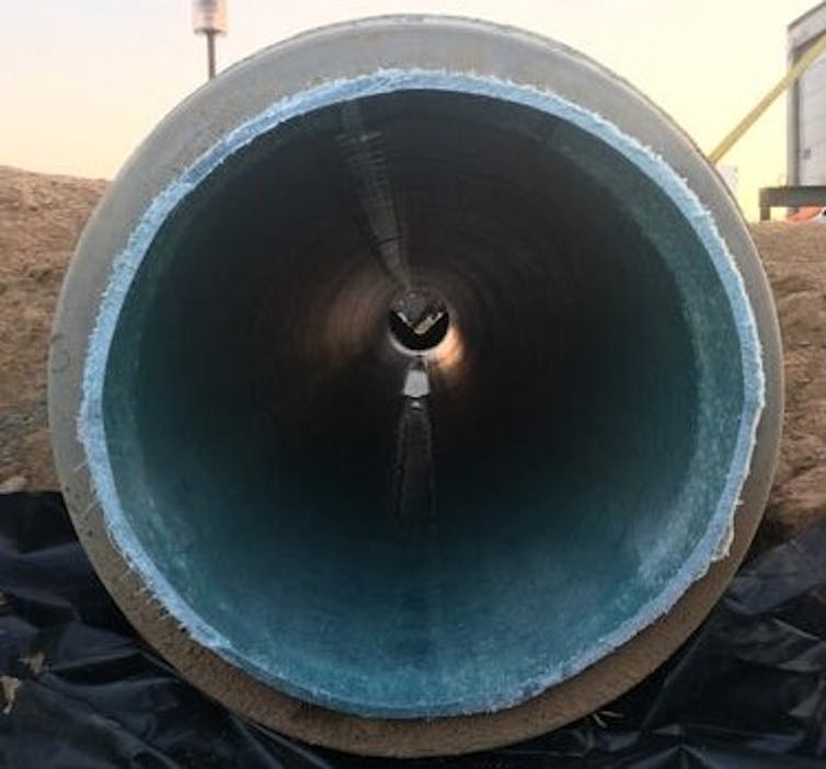 A face-on view into a sewer pipe, with a blue lining visible within the outer gray wall.