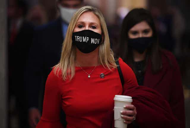 A woman in a red dress wearing a mask saying "Trump won".