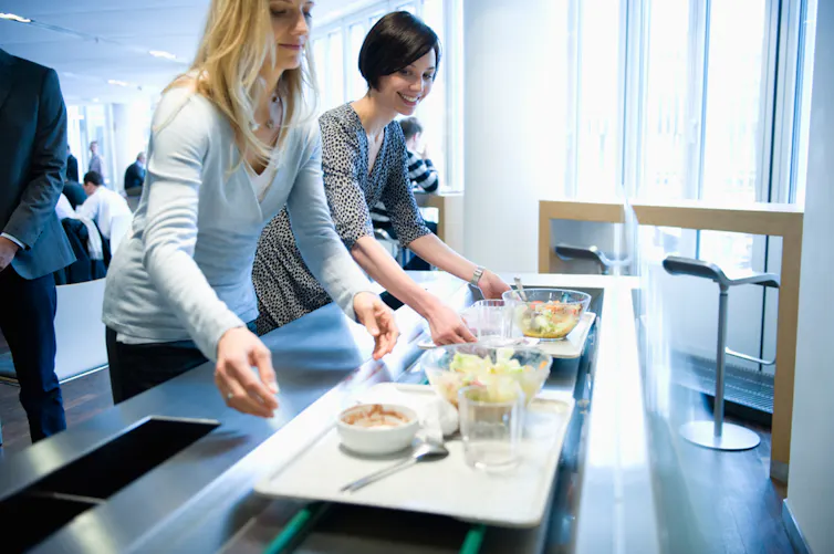 Business people with lunch trays in work cafeteria.