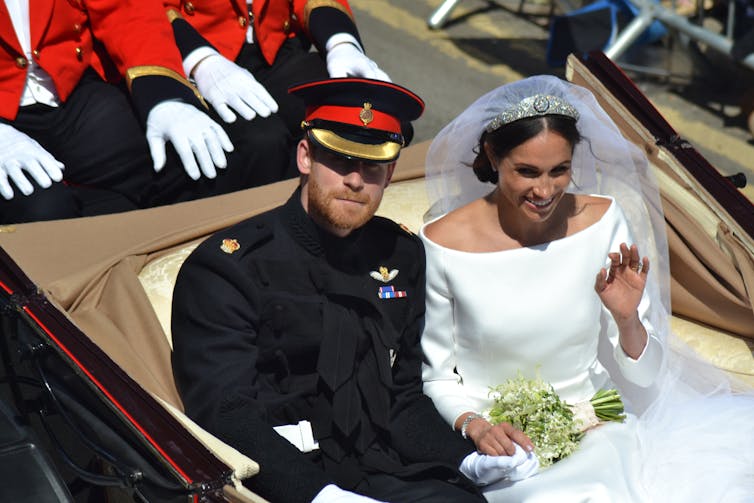 A bridal couple in an open-topped carriage.