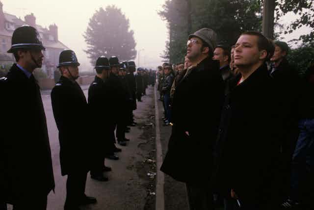 A line of police facing a line of striking miners on a foggy street in the 1980s. 
