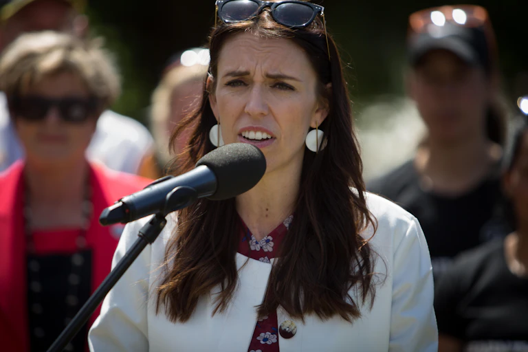 A woman in a white jacket at a microphone