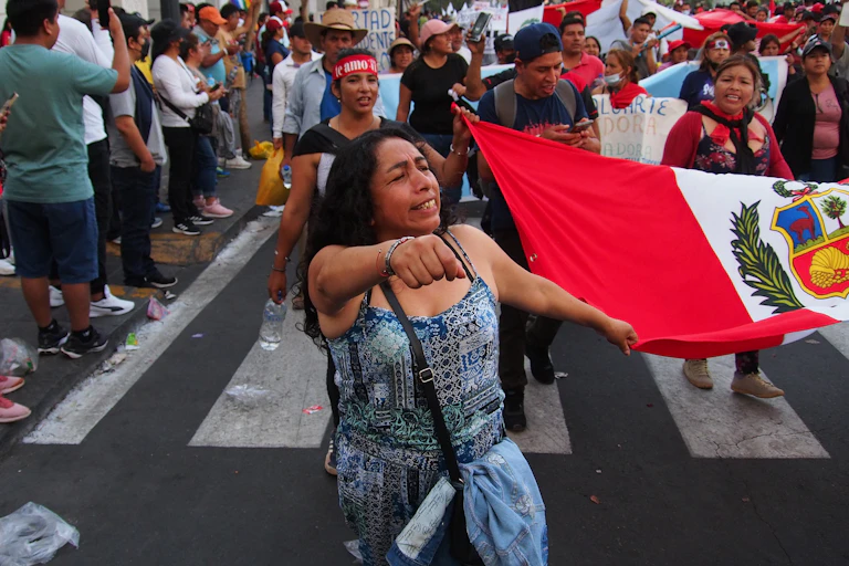 A woman raises her fist as she marches down a street with fellow protesters behind her.