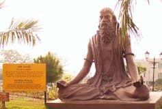 A statue of a man sitting with legs crossed.