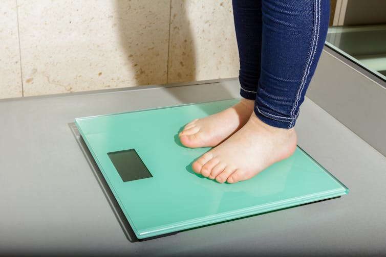 A child's feet stand on a digital scale.
