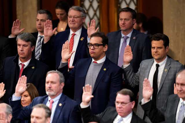 A group of men with their right hands raised.