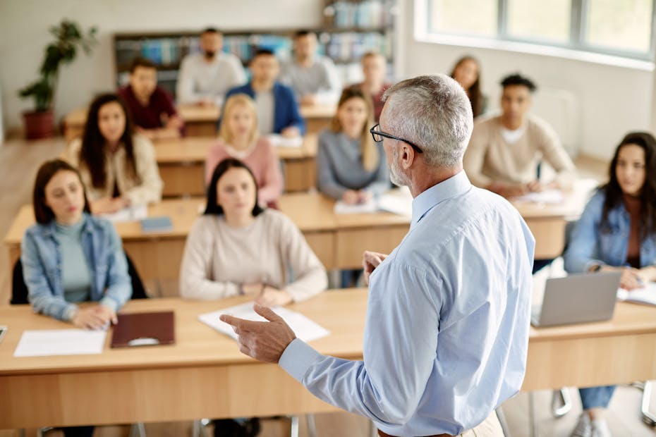 A man speaks to a classroom of students.