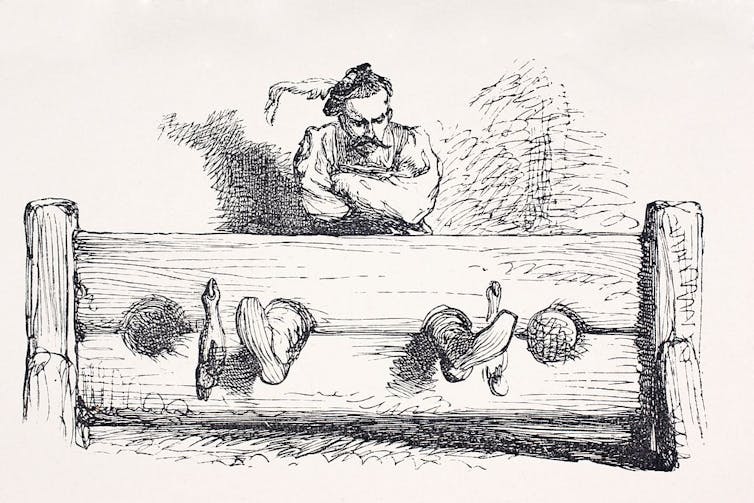 A black and white sketch shows a grumpy-looking man in stocks.