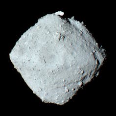 A greyscale rhomboid object with a dusty surface on a black background