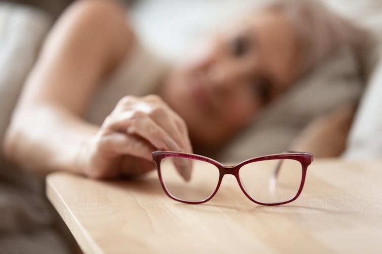 woman waking up and reaching for glasses