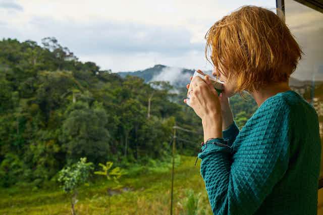 woman sips morning coffee looking at outdoors