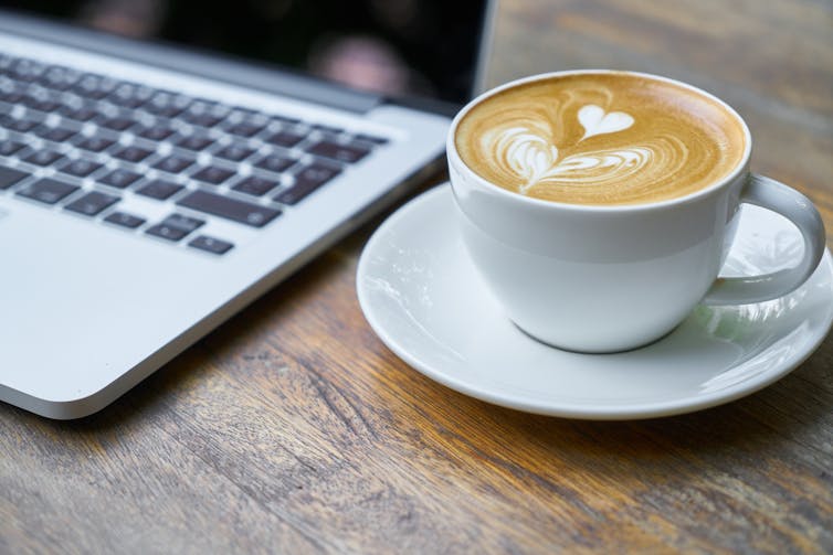 فنجان قهوه در کنار لپ تاپ