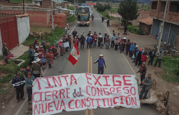 Peruvian protesters block a major road and hold up a banner calling for the closure of congress.
